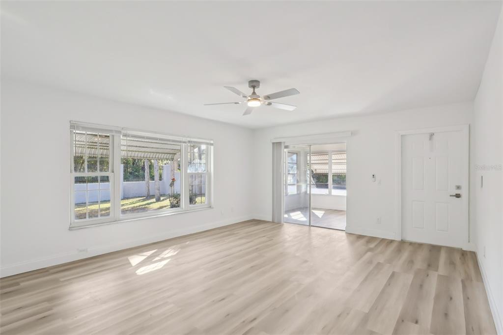 An empty room with light wood-look flooring, a ceiling fan, large windows, and a sliding door — 11147 ACME DRIVE UNIT D, ORLANDO, FL