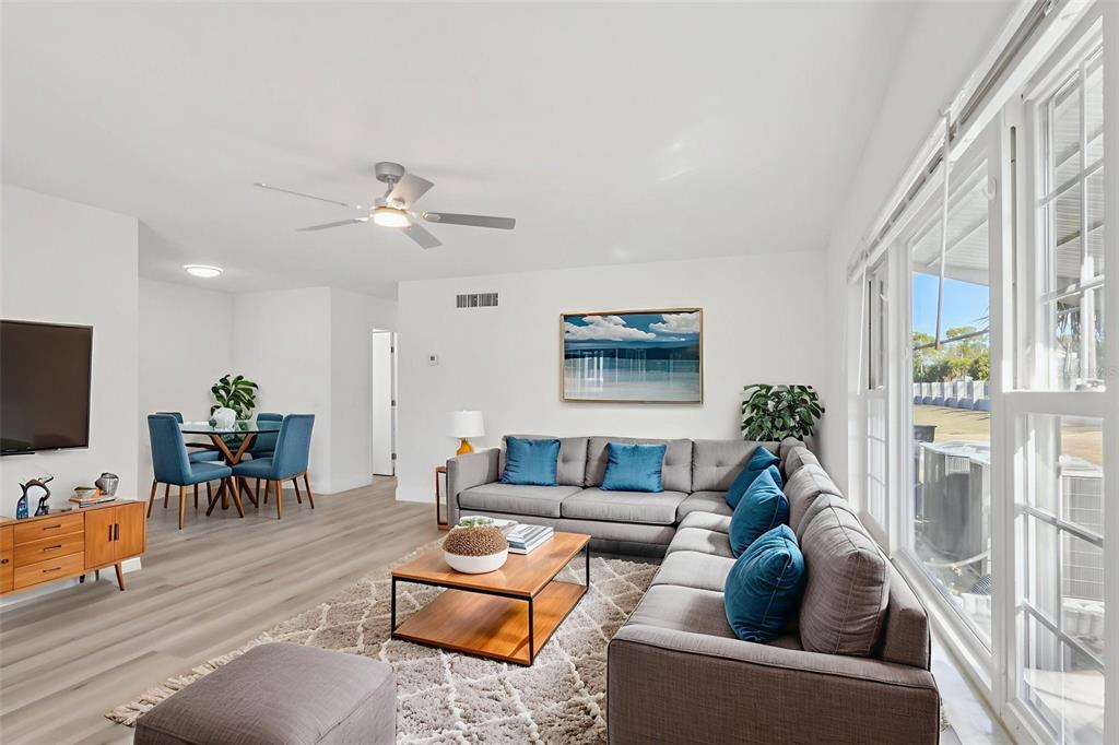 A living room with a gray sectional sofa, wood coffee table, and dining area — 11147 ACME DRIVE UNIT D, ORLANDO, FL