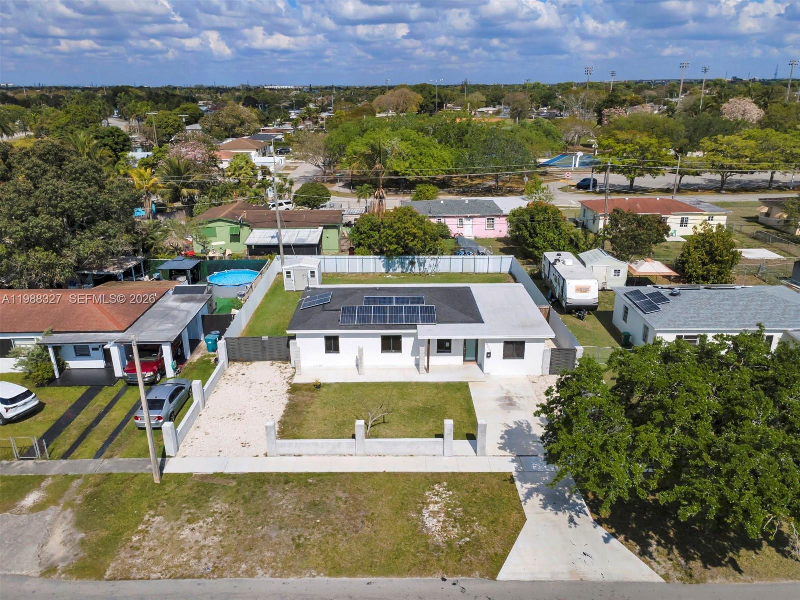 An aerial view shows a white house with solar panels and a fenced front yard — 14520 Carver Drive, Miami FL 33176, MIAMI, FL