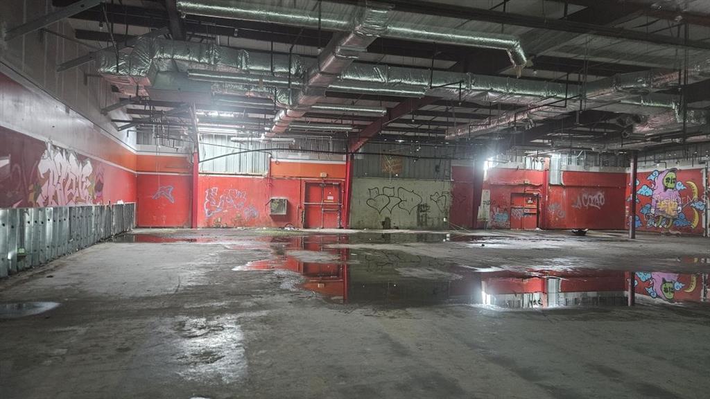 An empty, dilapidated commercial interior features graffiti-covered red walls, exposed ductwork, and standing water — 97 SATURNINO RODRIGUEZ #97, YABUCOA, PR