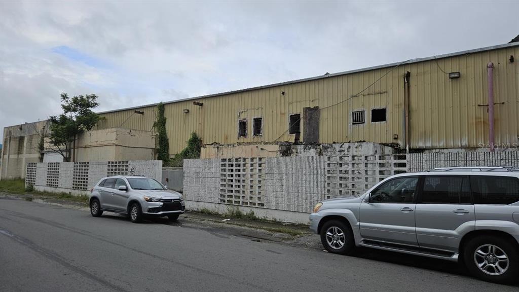 A street-level view of a weathered industrial building with a concrete block wall and cars — 97 SATURNINO RODRIGUEZ #97, YABUCOA, PR
