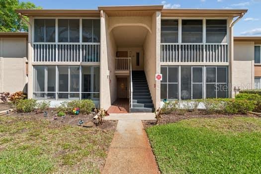 A two-story apartment building exterior features a central staircase leading to upper-level units — 13103 CYPRESS HILL DRIVE UNIT B2, HUDSON, FL