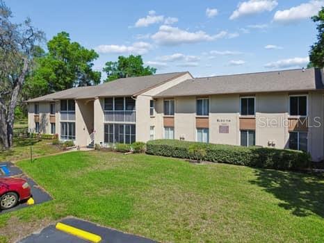 A two-story apartment building with tan siding and a parking lot in the foreground — 13103 CYPRESS HILL DRIVE UNIT B2, HUDSON, FL
