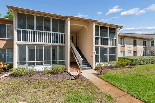 A two-story apartment building features screened-in balconies and an exterior staircase leading to the entrance — 13103 CYPRESS HILL DRIVE UNIT B2, HUDSON, FL