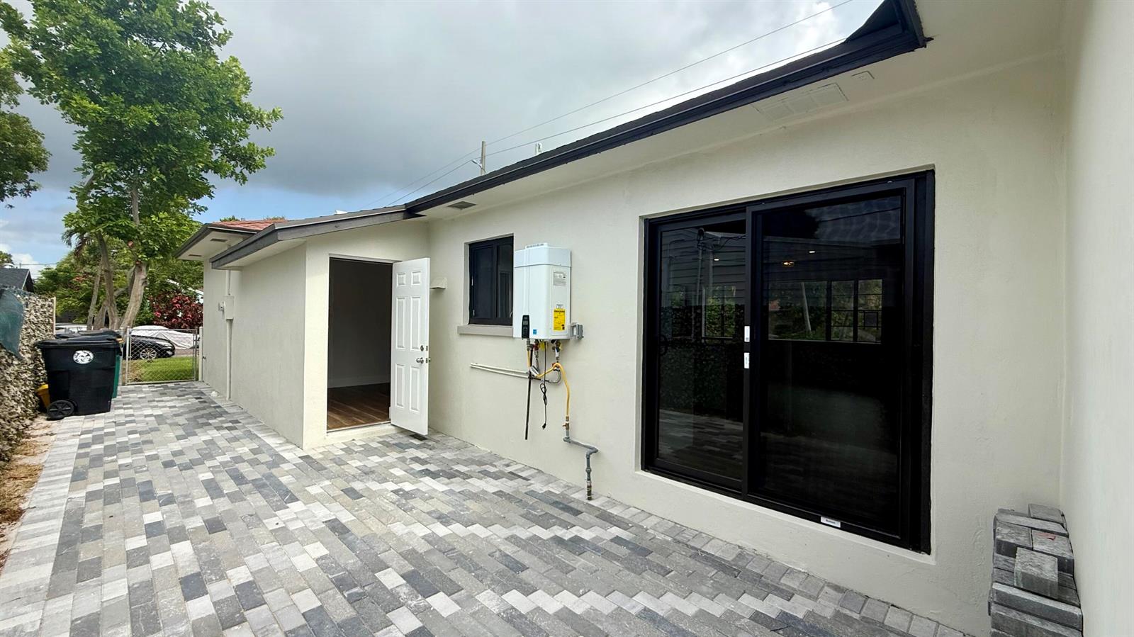 A paved patio area features a white exterior wall with a sliding door and water heater — 1130 N K Street, FL 33460, FL
