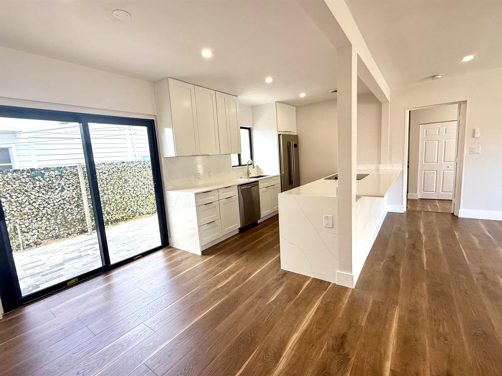 A modern kitchen features white cabinets, quartz countertops, stainless steel appliances, and wood-look flooring — 1130 N K Street, FL 33460, FL