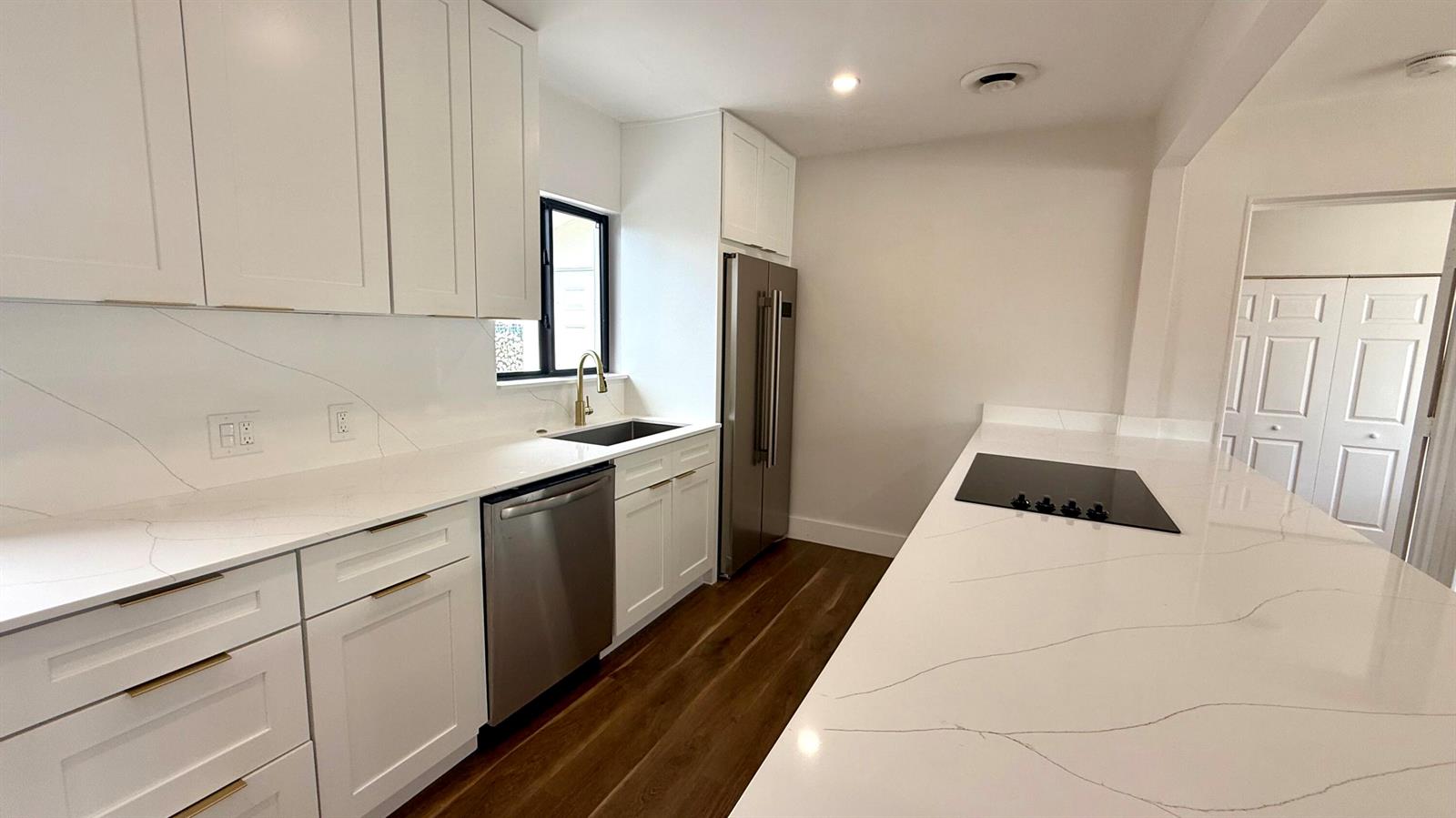 A modern kitchen features white cabinets, quartz countertops, stainless steel appliances, and dark wood flooring — 1130 N K Street, FL 33460, FL