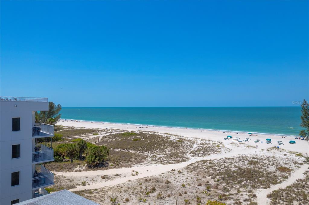 An elevated view of a sandy beach, dunes, and ocean next to a residential building — 10116 GULF BOULEVARD UNIT 403W, TREASURE ISLAND, FL