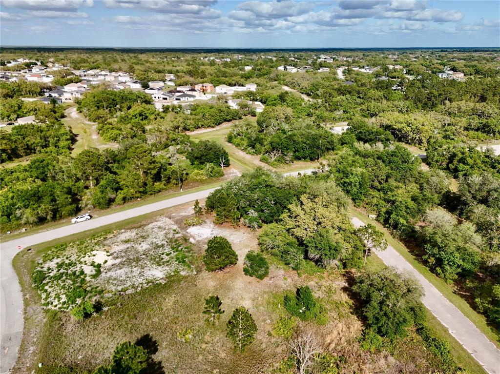 An aerial view shows a vacant, partially wooded lot situated between two paved roads — 634 MEDITERRANEAN COURT, KISSIMMEE, FL