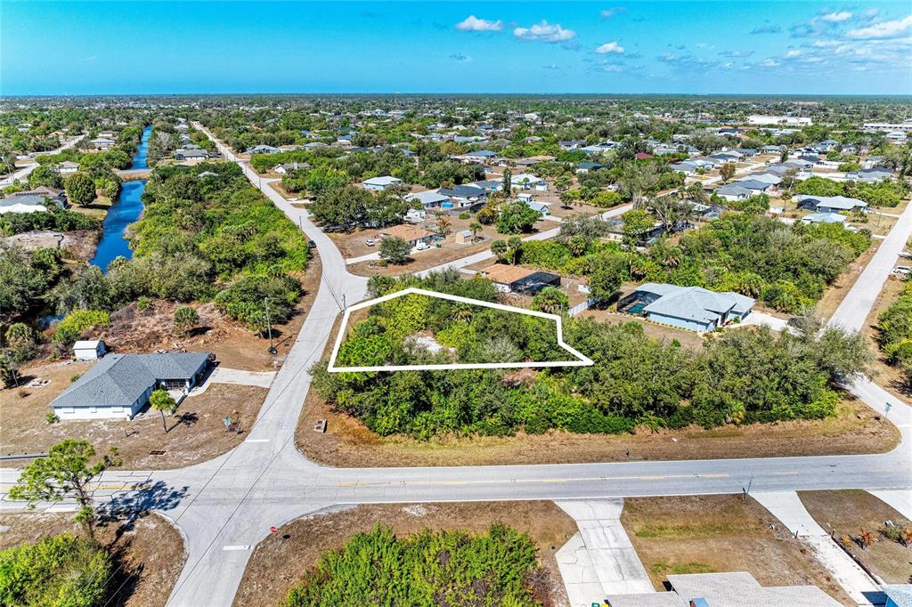 An aerial view shows a vacant, wooded residential lot outlined in white at a street intersection — 7376 REGINA DRIVE, ENGLEWOOD, FL