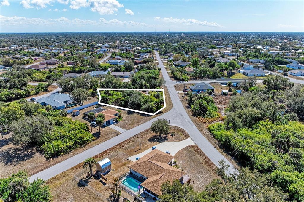 An aerial view shows a vacant, tree-covered lot outlined in white within a residential neighborhood — 7376 REGINA DRIVE, ENGLEWOOD, FL