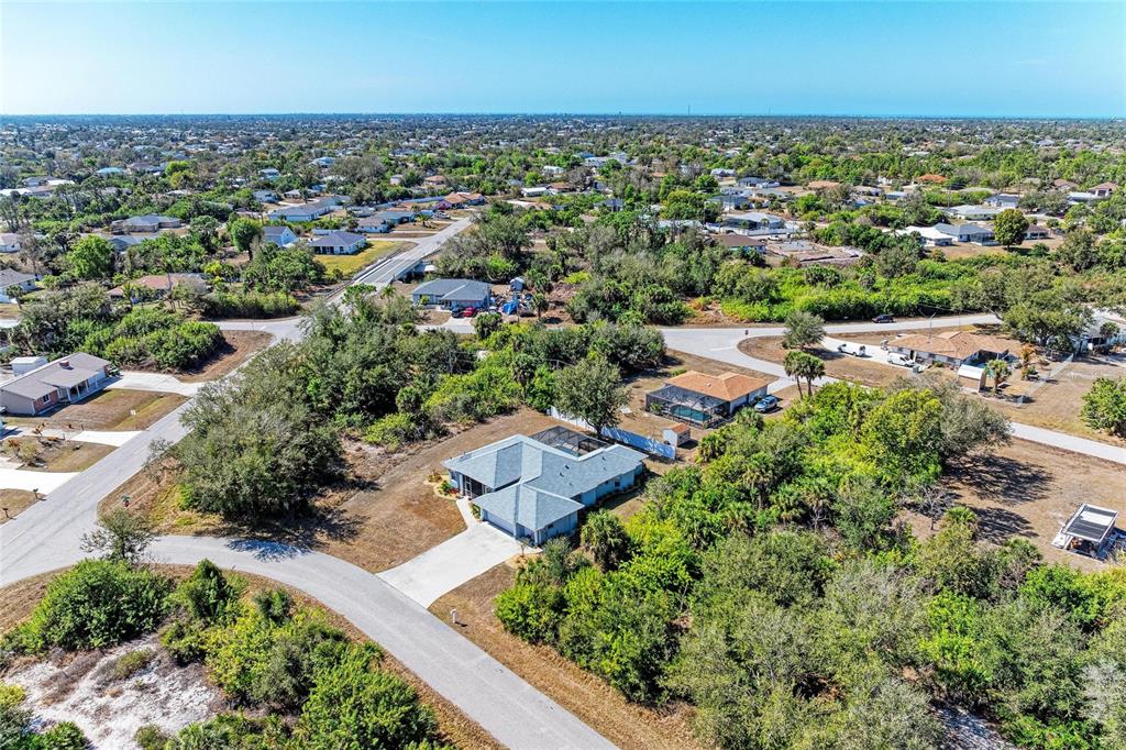 An aerial view shows a suburban house with a pool enclosure surrounded by dense vegetation — 7376 REGINA DRIVE, ENGLEWOOD, FL