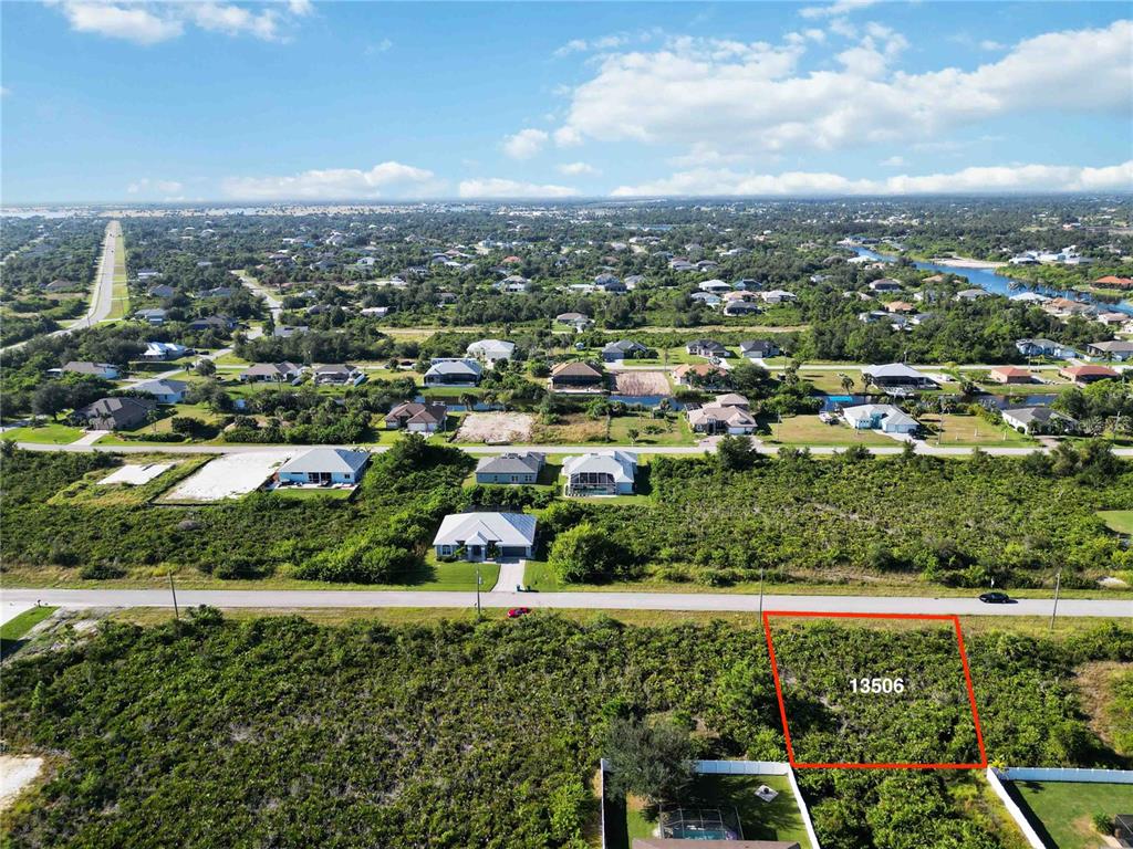 An aerial view shows a vacant, rectangular lot outlined in red next to a paved road — 13506 ABUTILON LANE, PORT CHARLOTTE, FL