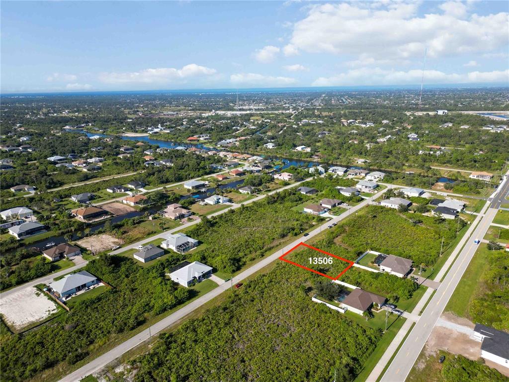 An aerial view shows a vacant, rectangular lot outlined in red within a residential neighborhood — 13506 ABUTILON LANE, PORT CHARLOTTE, FL