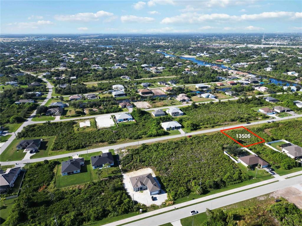 An aerial view shows a vacant residential lot outlined in red within a suburban neighborhood — 13506 ABUTILON LANE, PORT CHARLOTTE, FL