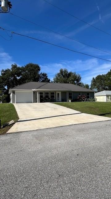 A single-story house with a metal roof and a concrete driveway under a blue sky — 1113 PORSCHE AVENUE, SEBRING, FL