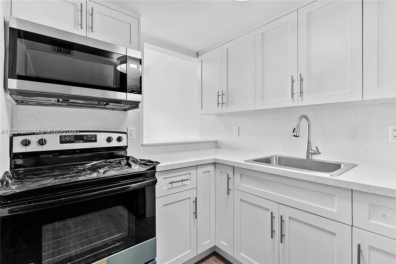 A kitchen features white cabinets, a stainless steel sink, and a black electric range — 1351 SW 4th St # 8, Miami FL 33135, MIAMI, FL