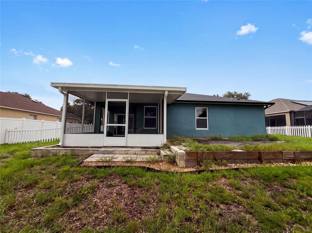 The exterior of a house features a screened-in porch and a raised garden bed — 12902 SCOUT COURT, GRAND ISLAND, FL