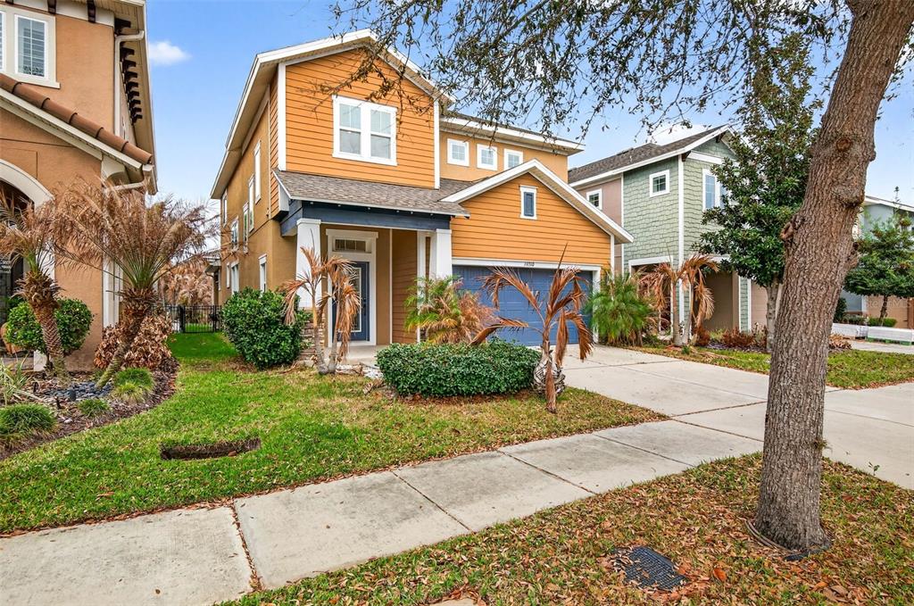 A two-story house with orange siding, a blue garage door, and a front lawn — 14310 BARRINGTON STOWERS DRIVE, LITHIA, FL