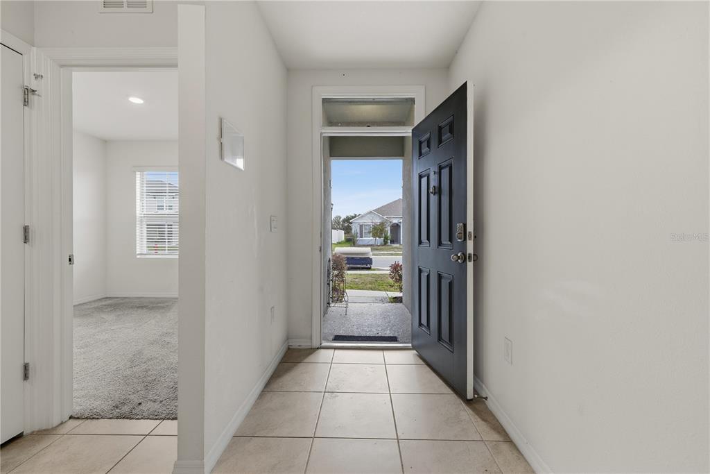 An entryway with tile flooring leads to an open front door and a carpeted room — 624 HONEY BELL ROAD, WINTER HAVEN, FL