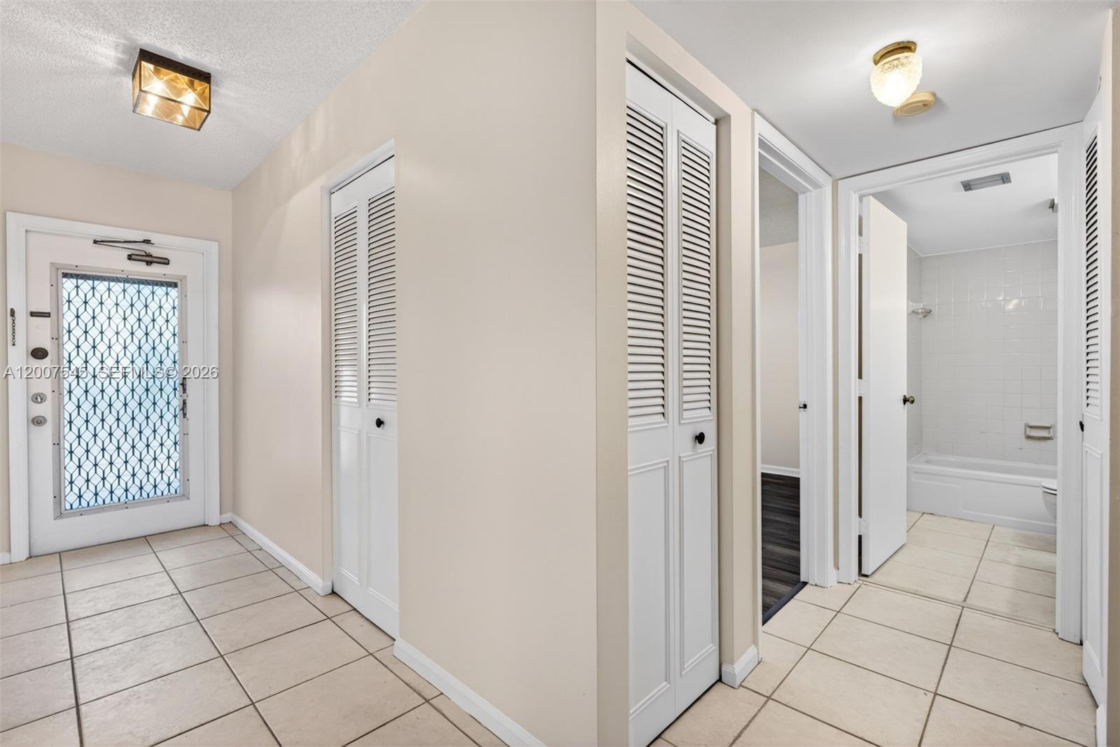A tiled entryway features two louvered closet doors, a front door, and a bathroom entrance — 357 N Rock Island Rd # 207, Margate FL 33063, MARGATE, FL