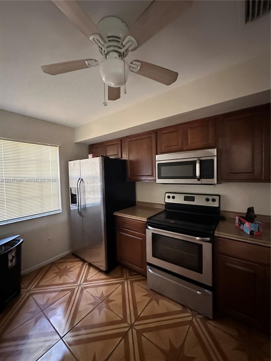 A kitchen features wood cabinets, stainless steel appliances, and patterned tile flooring — 2012 Champions Way, North Lauderdale FL 33068, NORTH LAUDERDALE, FL