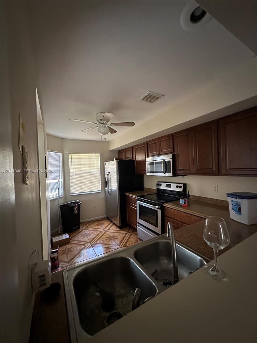 A kitchen features dark wood cabinets, stainless steel appliances, a double sink, and tiled floors — 2012 Champions Way, North Lauderdale FL 33068, NORTH LAUDERDALE, FL