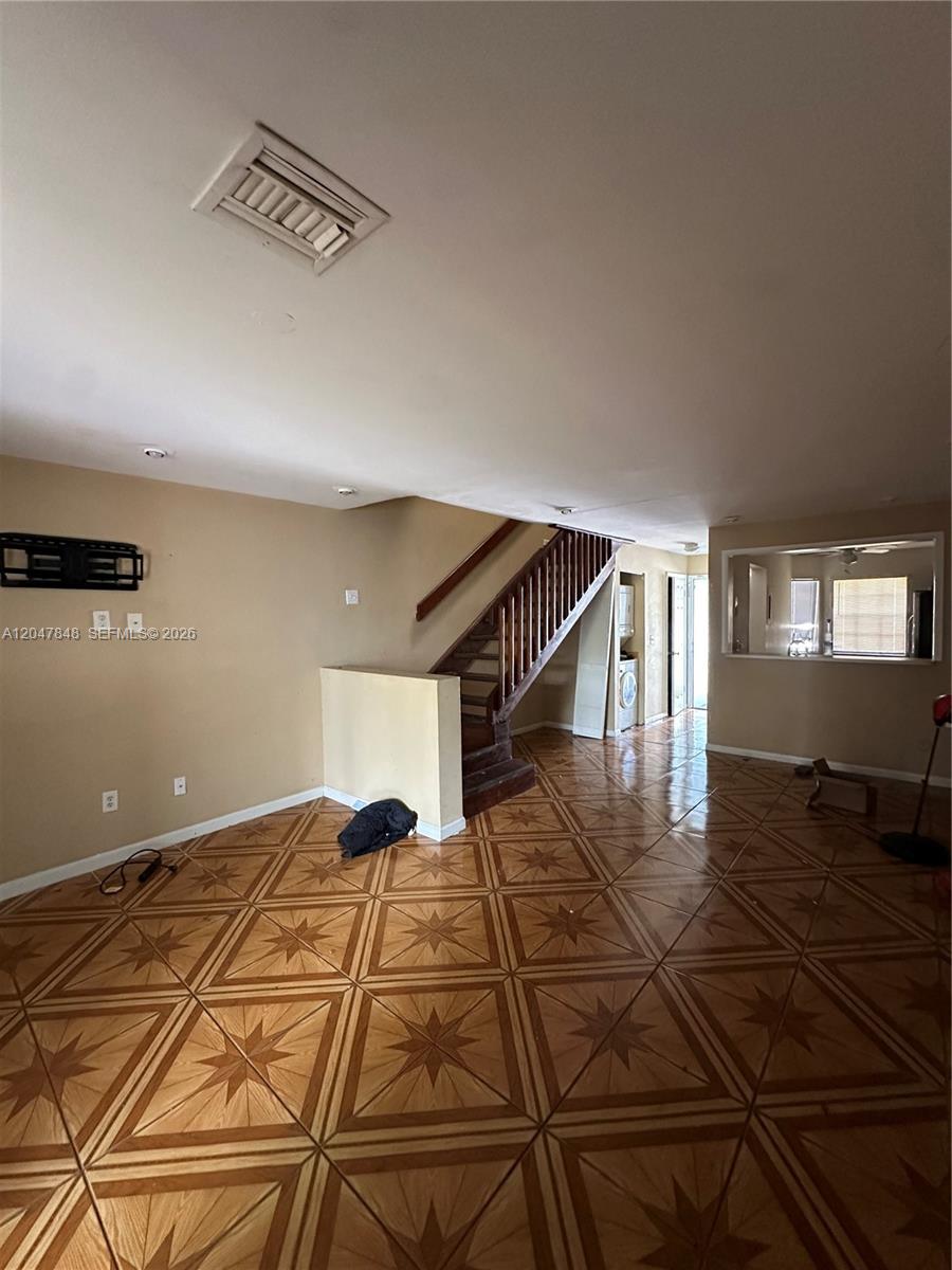 An interior view of a living room with tiled floors, a staircase, and a pass-through window — 2012 Champions Way, North Lauderdale FL 33068, NORTH LAUDERDALE, FL