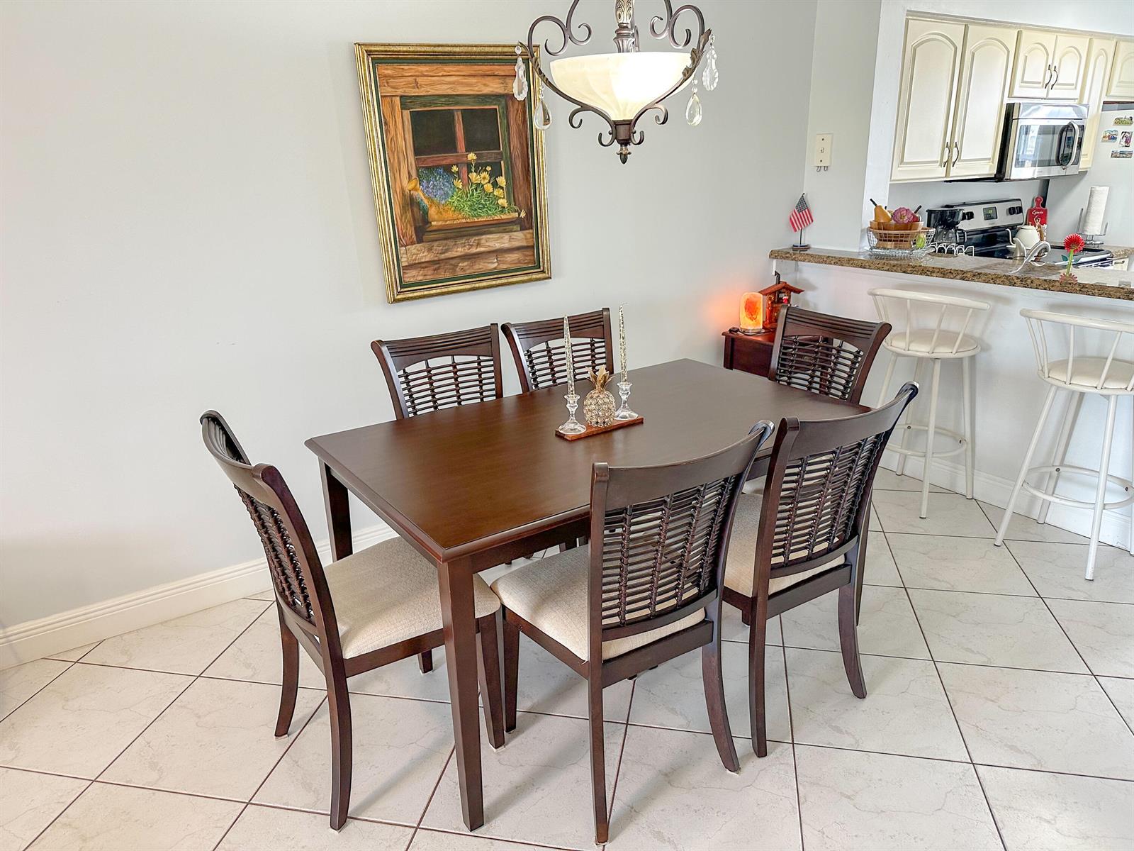 A dining area features a dark wood table with six chairs and a hanging chandelier — 2222 N Cypress Bend Drive # 403, Pompano Beach FL 33069, POMPANO BEACH, FL