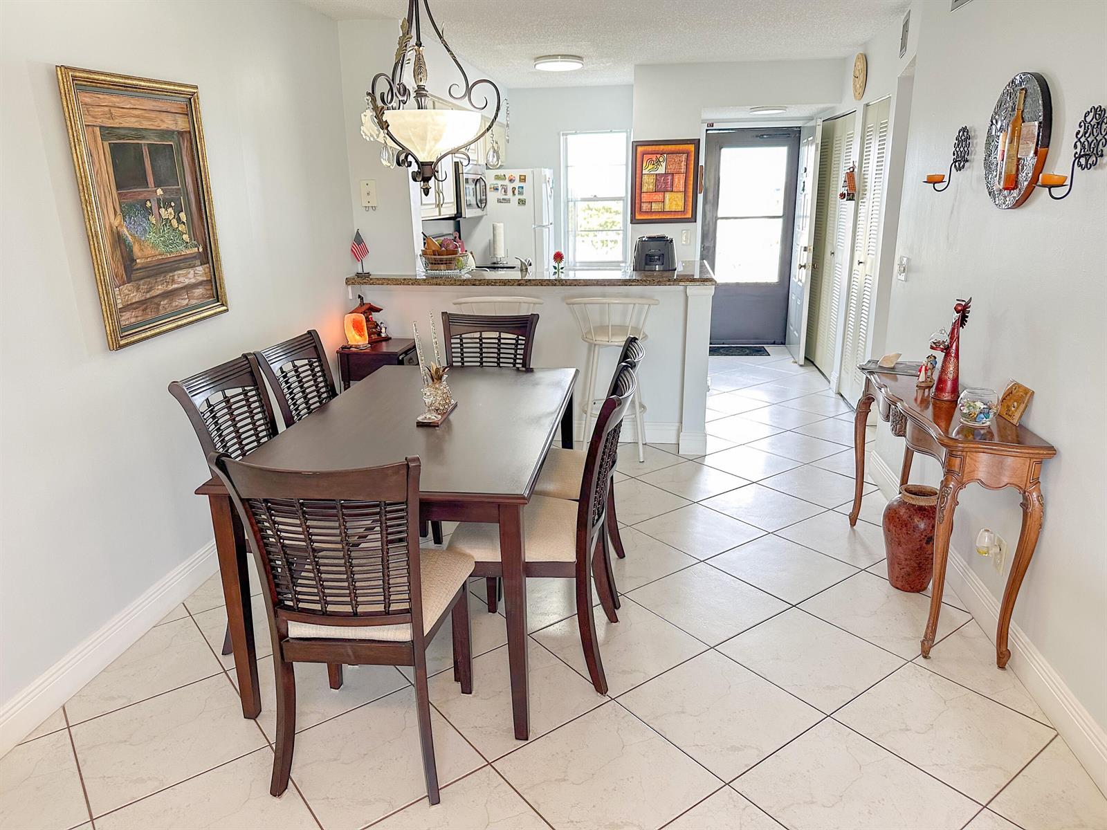 A dining room with a dark wood table, woven chairs, and tile flooring — 2222 N Cypress Bend Drive # 403, Pompano Beach FL 33069, POMPANO BEACH, FL