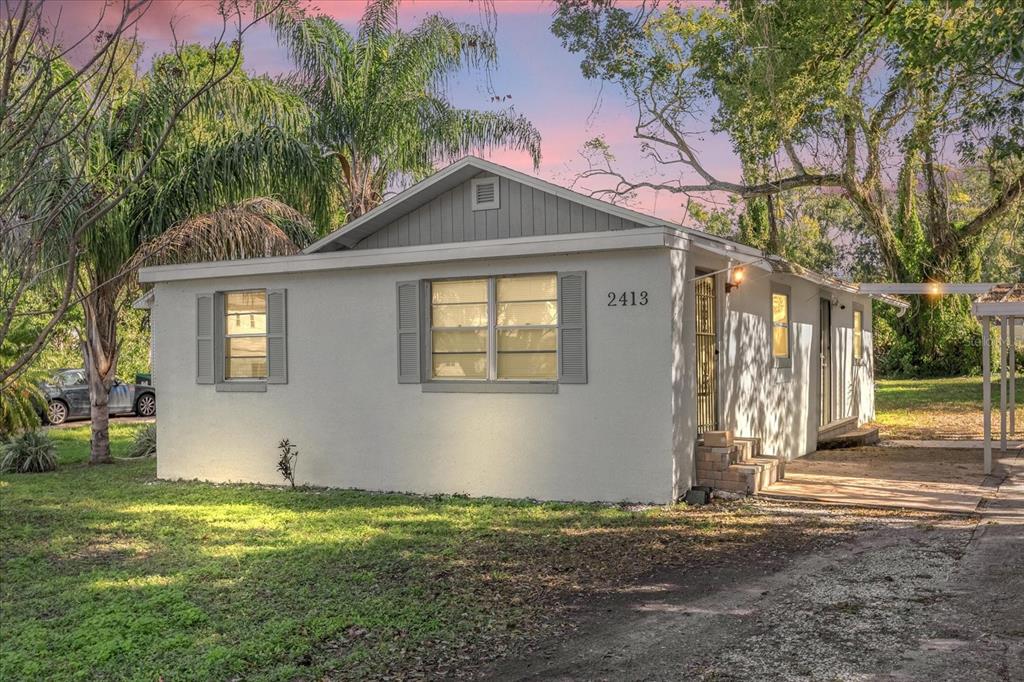 A single-story house with a white stucco exterior, gray shutters, and a metal carport — 2413 MARLBORO STREET, ORLANDO, FL