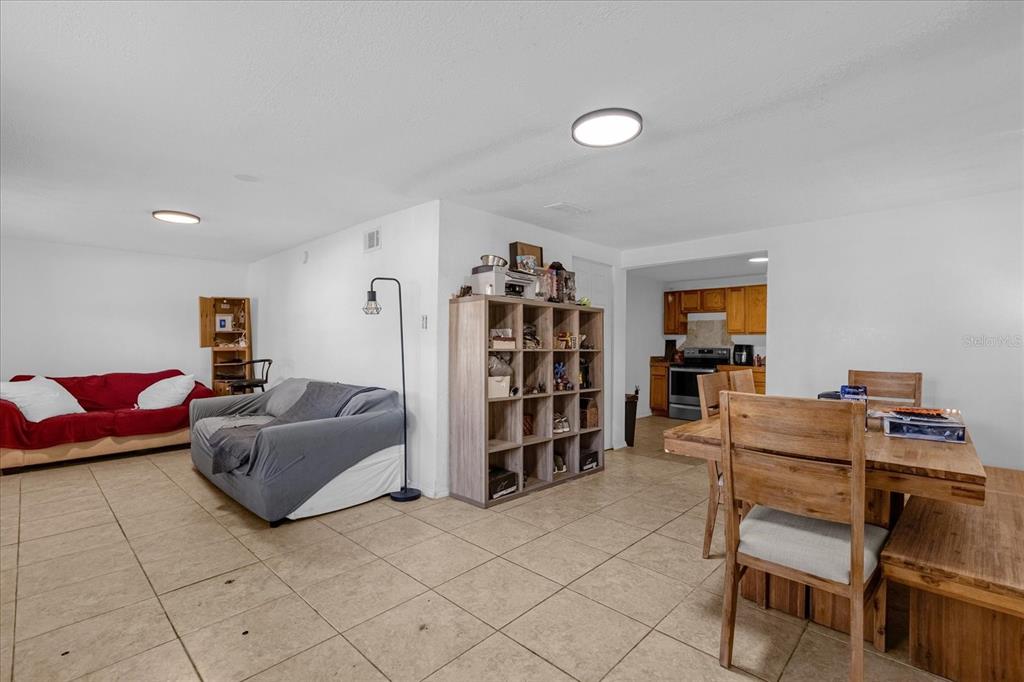 A living room with tile floors, a grey sofa, and an adjacent dining area — 2413 MARLBORO STREET, ORLANDO, FL