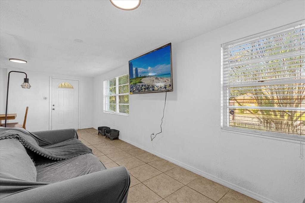 A living room features a wall-mounted television, tiled flooring, and two windows with blinds — 2413 MARLBORO STREET, ORLANDO, FL