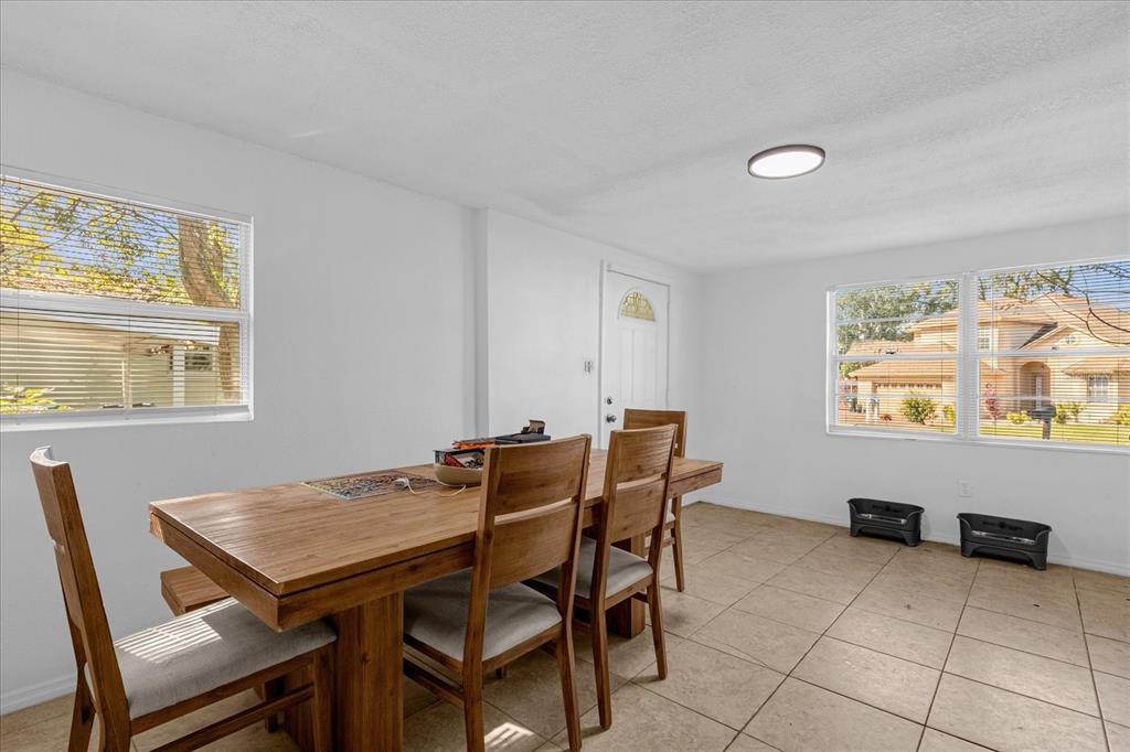 A dining room with tile floors, a wooden table, and windows overlooking a residential street — 2413 MARLBORO STREET, ORLANDO, FL