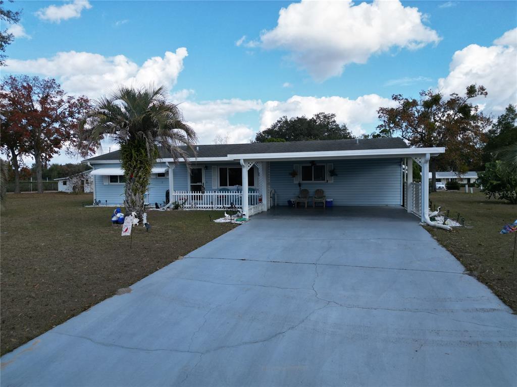 A light blue single-story house features a front carport, a concrete driveway, and a palm tree — 10041 SW 97TH COURT, OCALA, FL