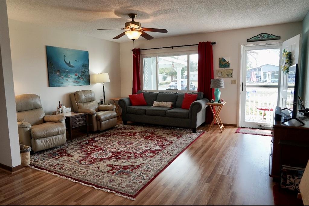 A living room features a gray sofa, two beige recliners, a patterned rug, and wood flooring — 10041 SW 97TH COURT, OCALA, FL