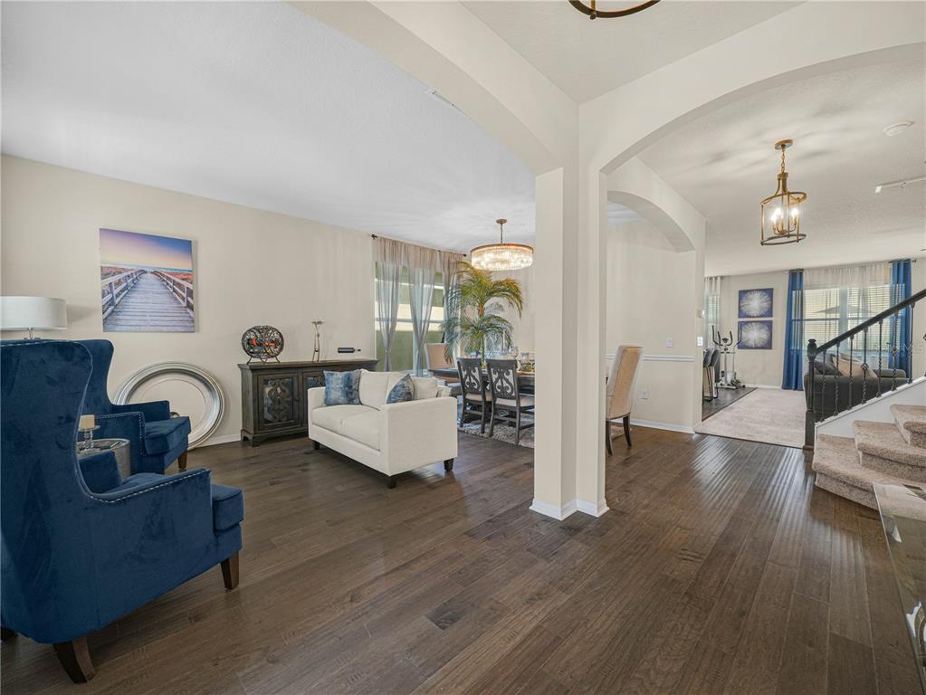 A living room features two blue velvet wingback chairs, a beige sofa, and a large mirror — 184 WHIRLAWAY DRIVE, DAVENPORT, FL
