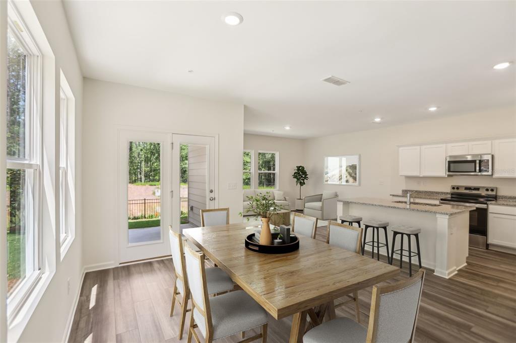 A dining area with a wooden table leads into an open kitchen and living space — 2570 GREY HAWK DRIVE,, KISSIMMEE, FL