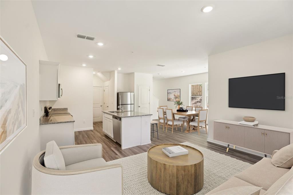 An open-concept living room and kitchen featuring light wood floors, white cabinetry, and neutral furniture — 2570 GREY HAWK DRIVE,, KISSIMMEE, FL