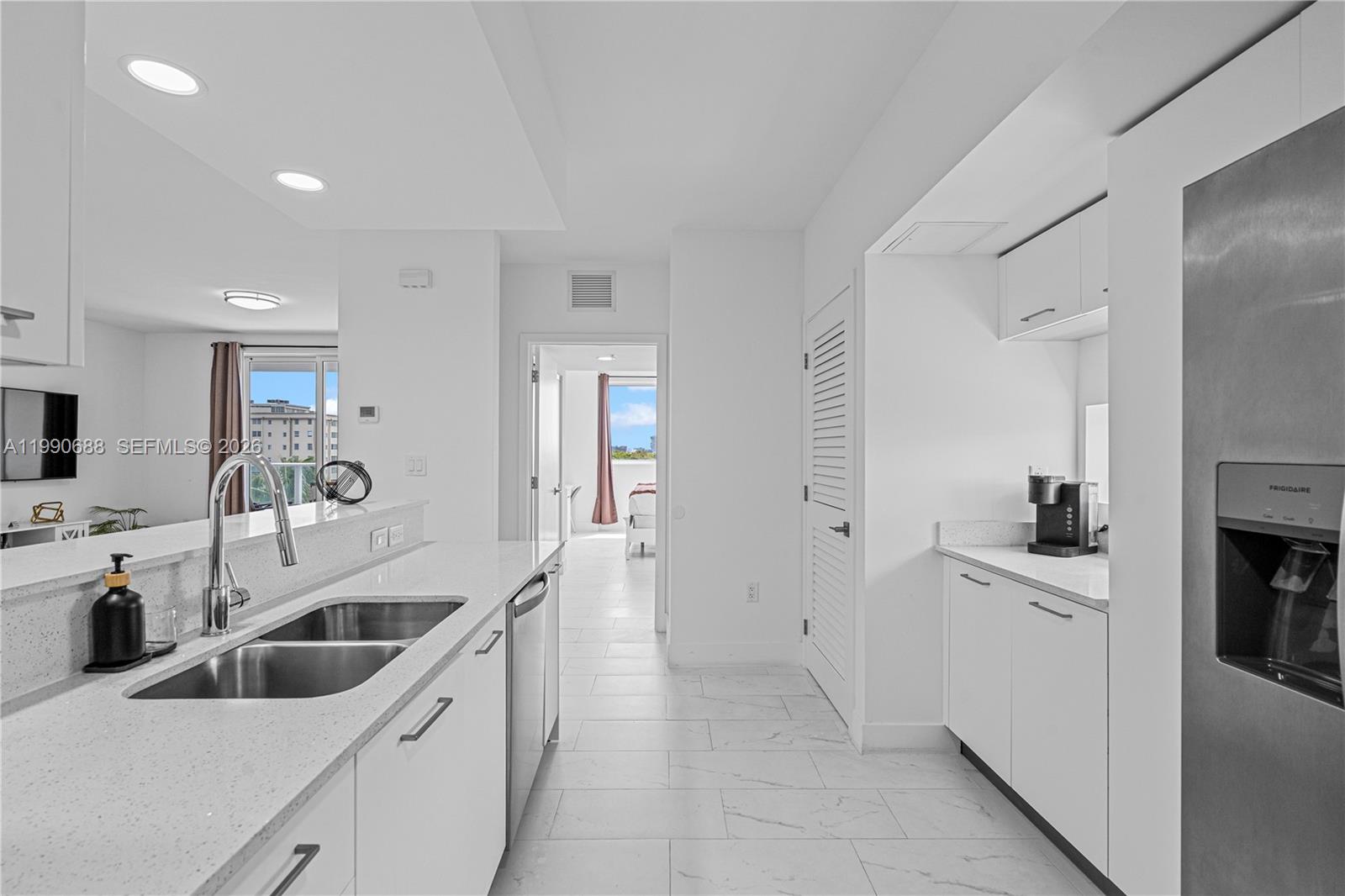 This kitchen features white cabinets, stainless steel appliances, and a view into a bedroom — 1850 Monroe St # 308, Hollywood FL 33020, HOLLYWOOD, FL