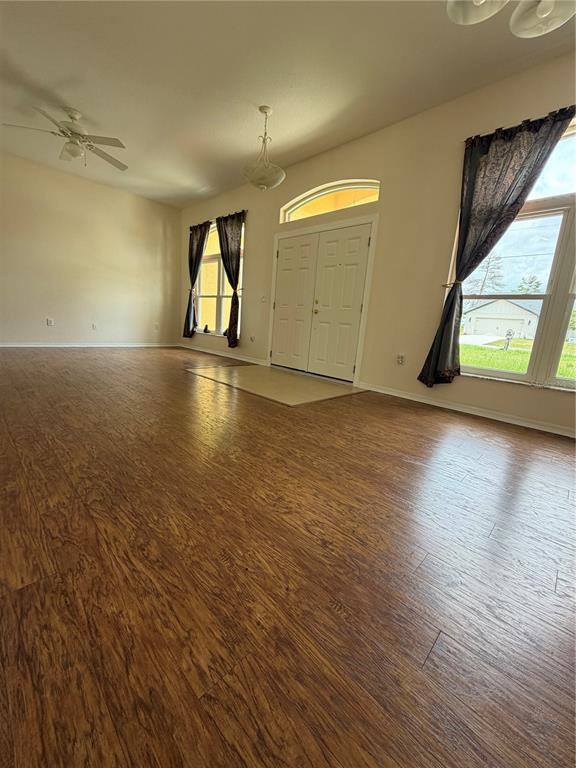 A living room features wood-look flooring, a ceiling fan, and double front doors — 18179 MABERLY  ROAD, WEEKI WACHEE, FL