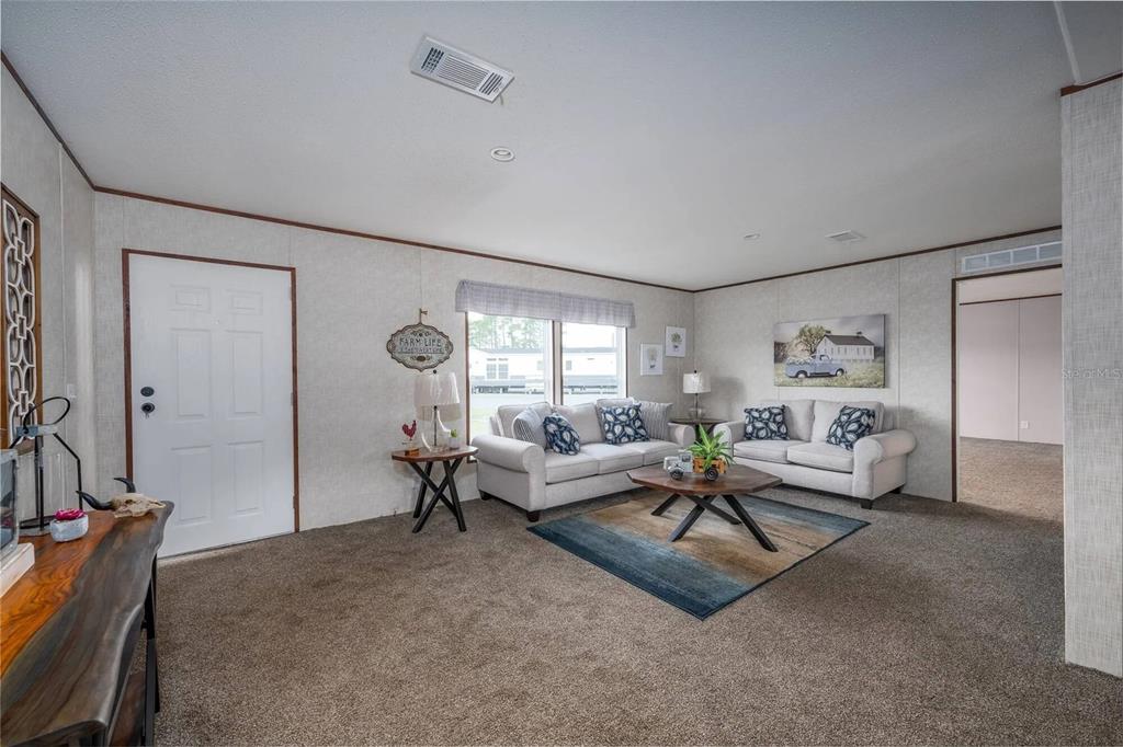 A living room features beige walls, brown carpeting, two light-colored sofas, and a wooden coffee table — 1065 NE COUNTY ROAD 125, LAWTEY, FL