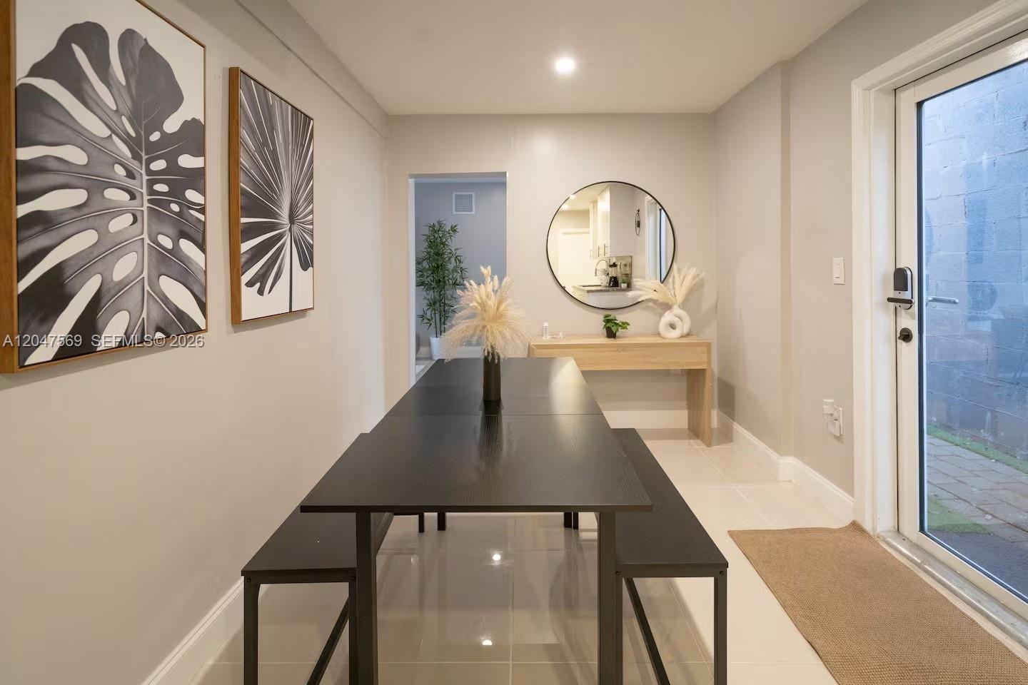 A dining area features a black table with benches, wall art, and a console table — 174 NE 55th St # 1, Miami FL 33137, MIAMI, FL
