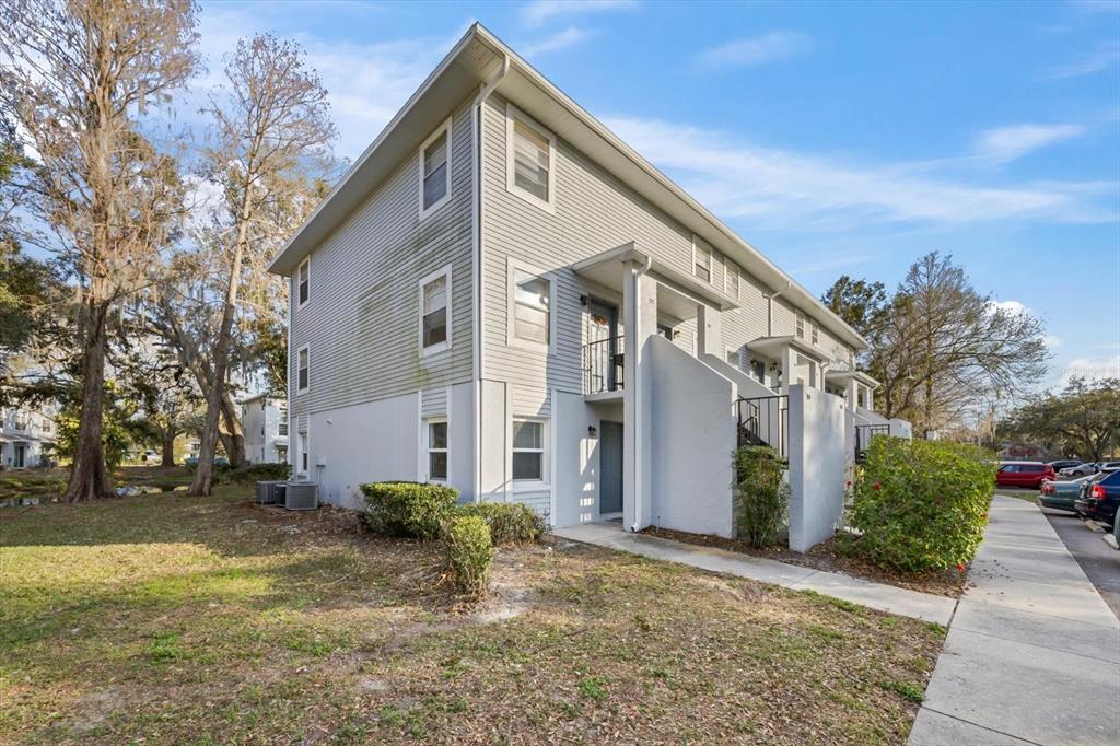 A two-story light gray siding apartment building with an exterior staircase and concrete walkway — 7169 E BANK DRIVE UNIT 7169, TAMPA, FL