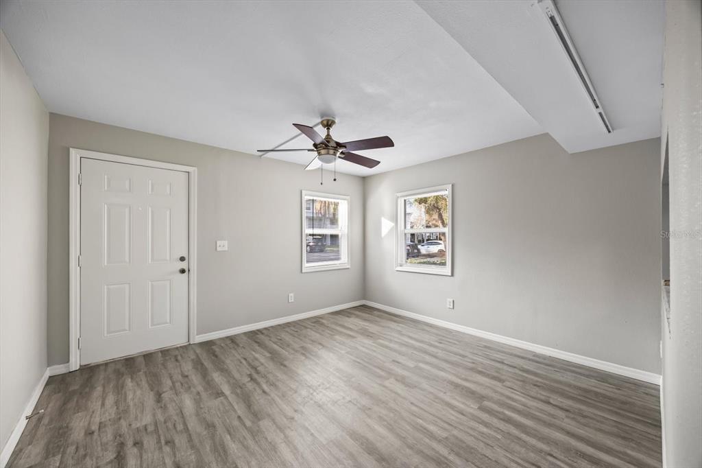 An empty room with light gray walls, wood-look flooring, a ceiling fan, and two windows — 7169 E BANK DRIVE UNIT 7169, TAMPA, FL