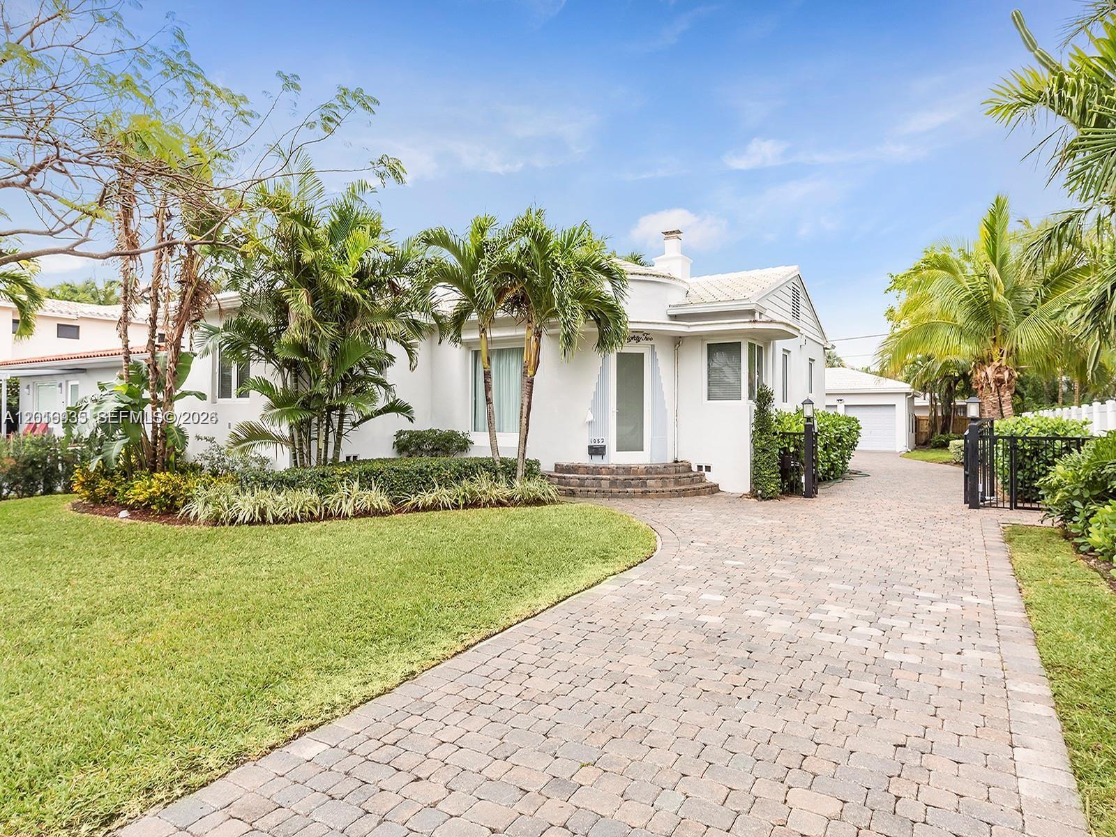 A white single-story house with a paved driveway, palm trees, and a manicured lawn — 1082 NE 89th St, Miami FL 33138, MIAMI, FL