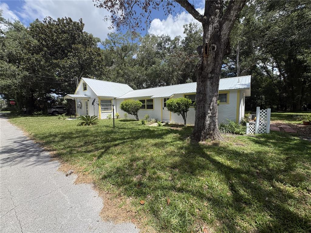 A white single-story house with a metal roof and yellow trim sits on a lawn — 490 JOHN STREET UNIT A & B, LAKE HELEN, FL