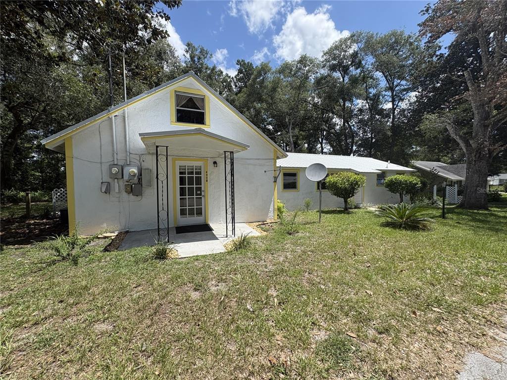 A white, single-story house with a metal roof and yellow trim sits on a lawn — 490 JOHN STREET UNIT A & B, LAKE HELEN, FL