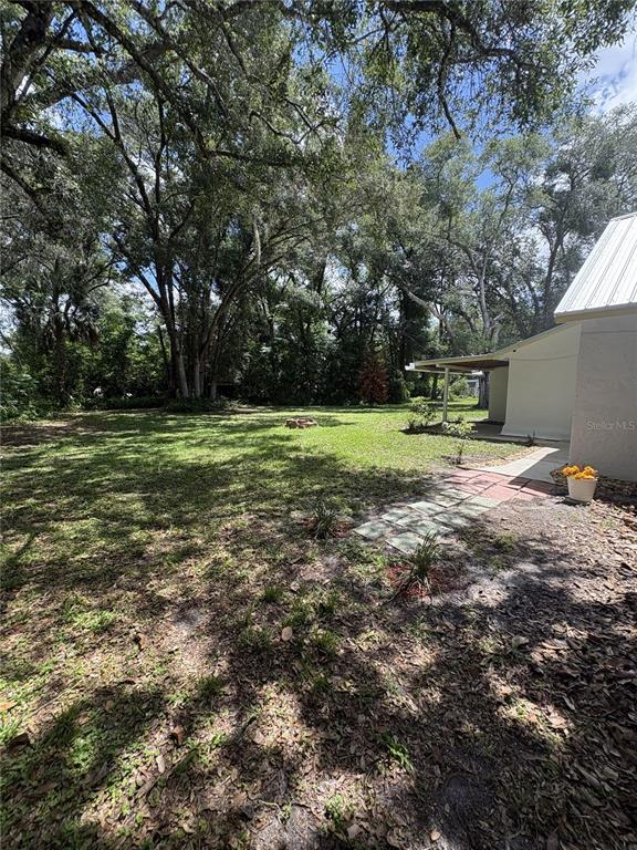 A small white house with yellow trim sits on a grassy lot under large trees — 490 JOHN STREET UNIT A & B, LAKE HELEN, FL