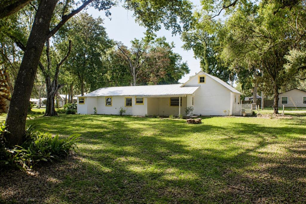 A white, single-story house with a metal roof sits on a large, tree-shaded lawn — 490 JOHN STREET UNIT A & B, LAKE HELEN, FL
